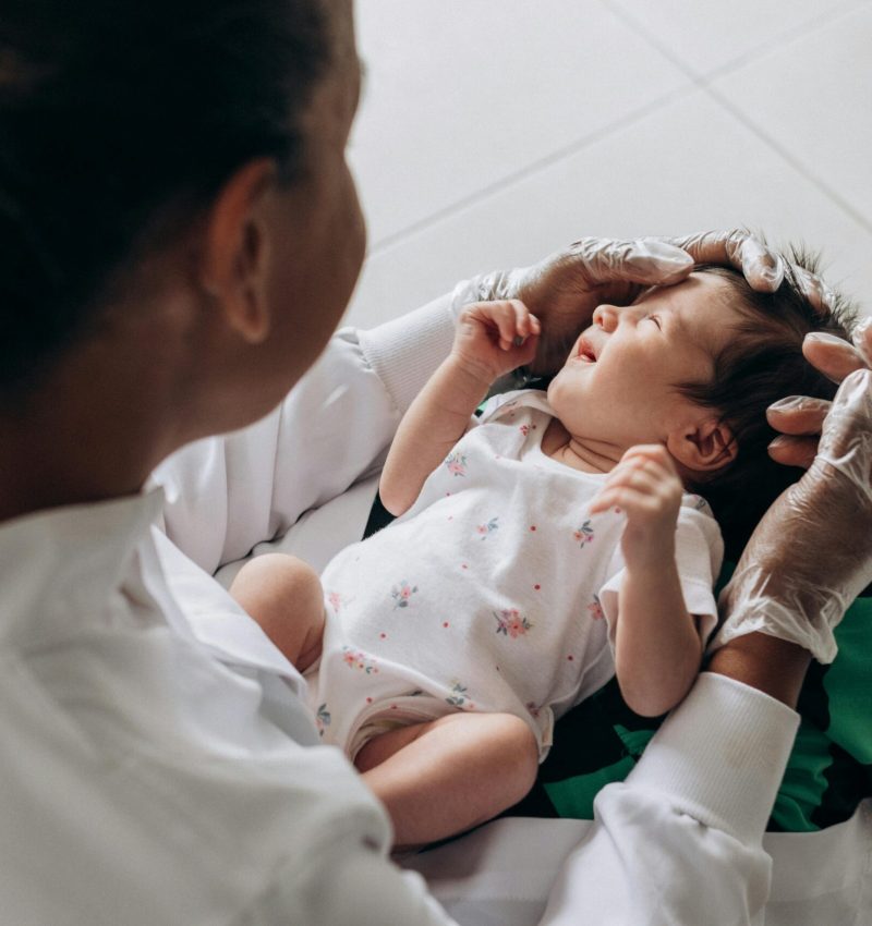A medical professional examines a newborn baby indoors, highlighting healthcare and care.